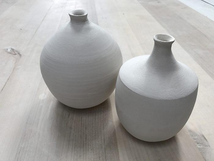 två stående vaser, båda är vita och hade en rund form.